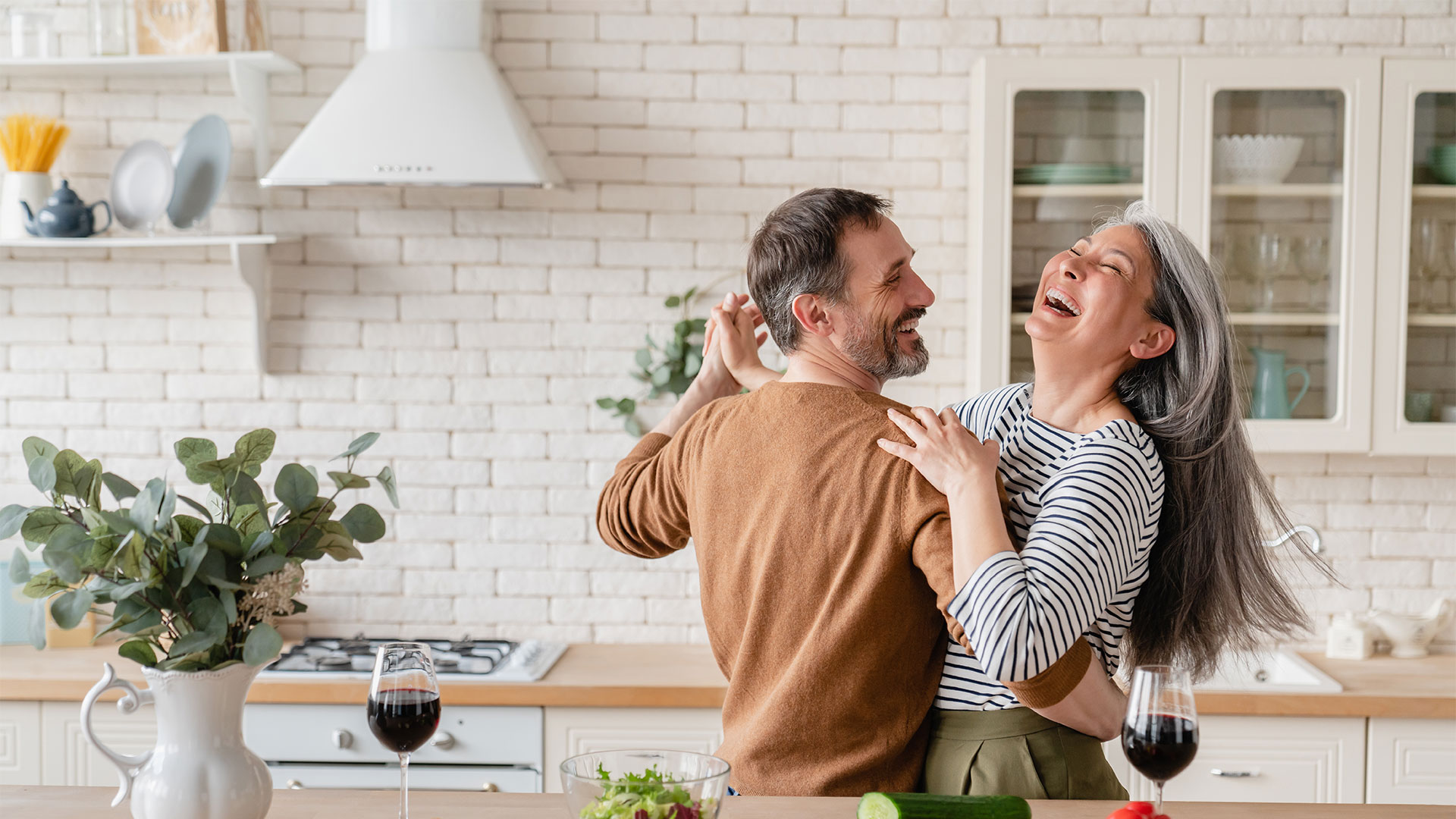 Happy middle-aged couple dancing in the kitchen